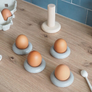 Sur plan travail cuisine quatre coquetiers béton forme bouée occupés quatre œufs support bois rangement