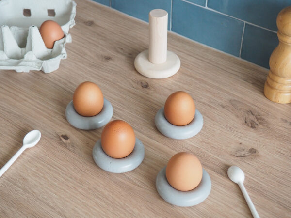 Sur plan travail cuisine quatre coquetiers béton forme bouée occupés quatre œufs support bois rangement