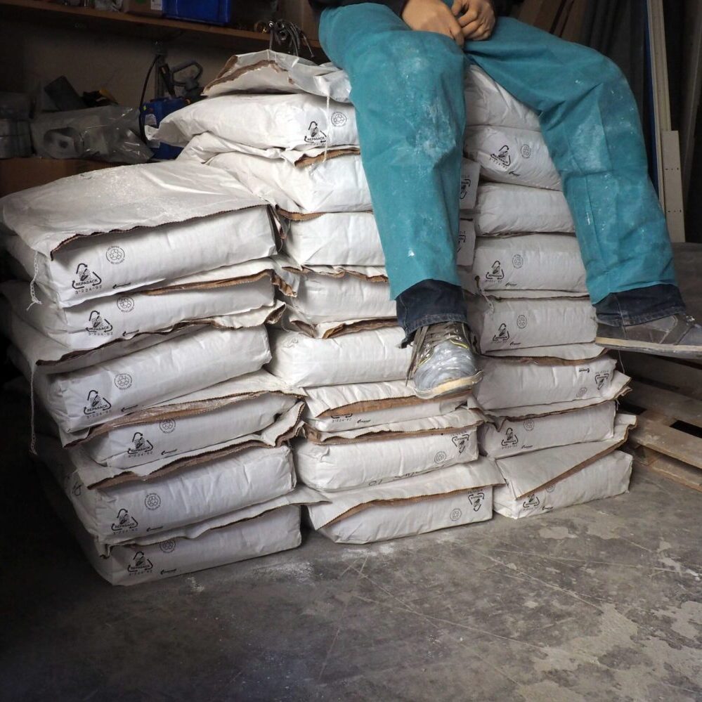 Homme artisan piles sacs béton atelier artisanat