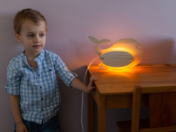 Lampe allumée bois clair forme baleine cordon blanc sur bureau écolier enfant